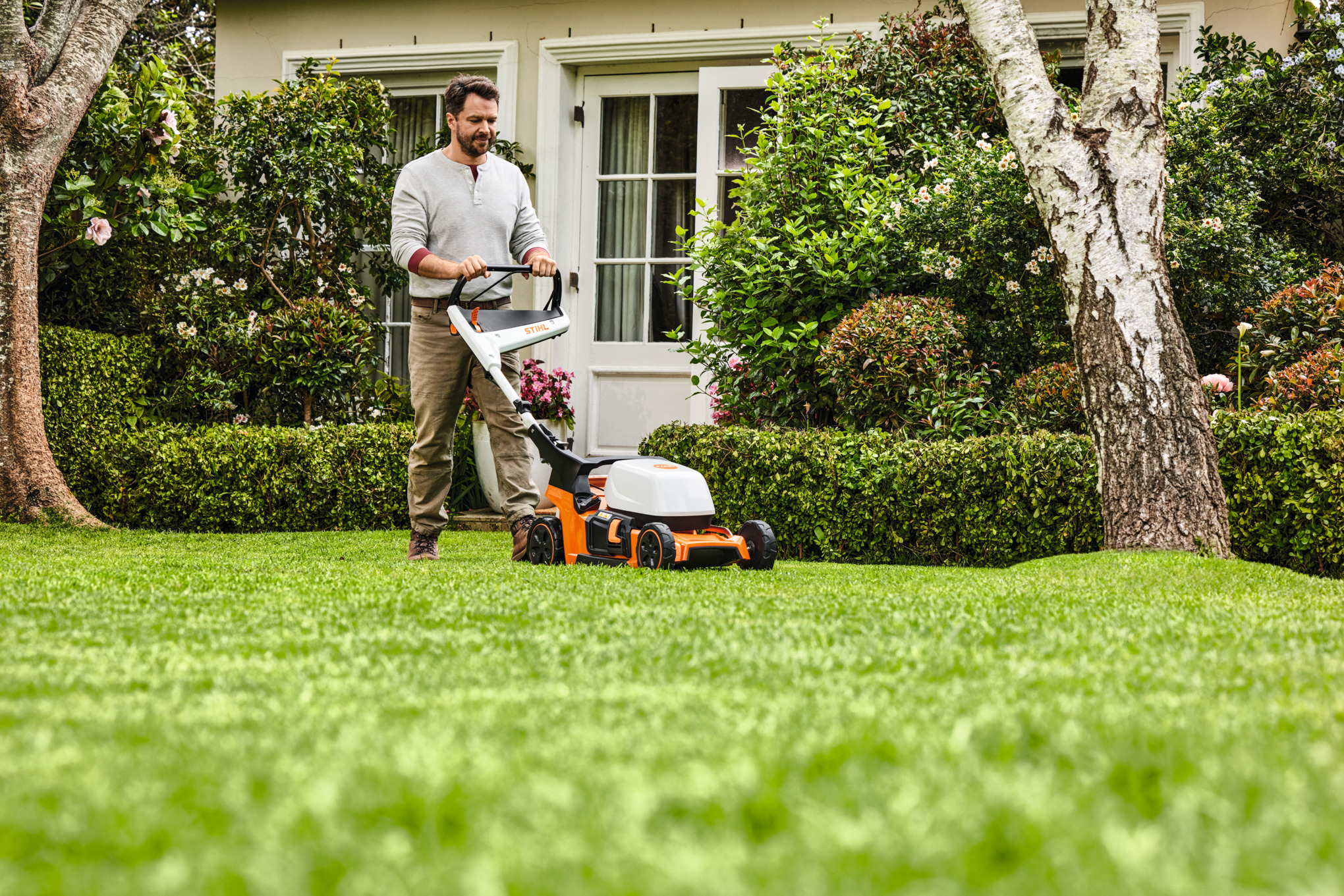 Vrouw bij het mulchen met een STIHL RM 2 R benzinemulchmaaier op een groen perceel