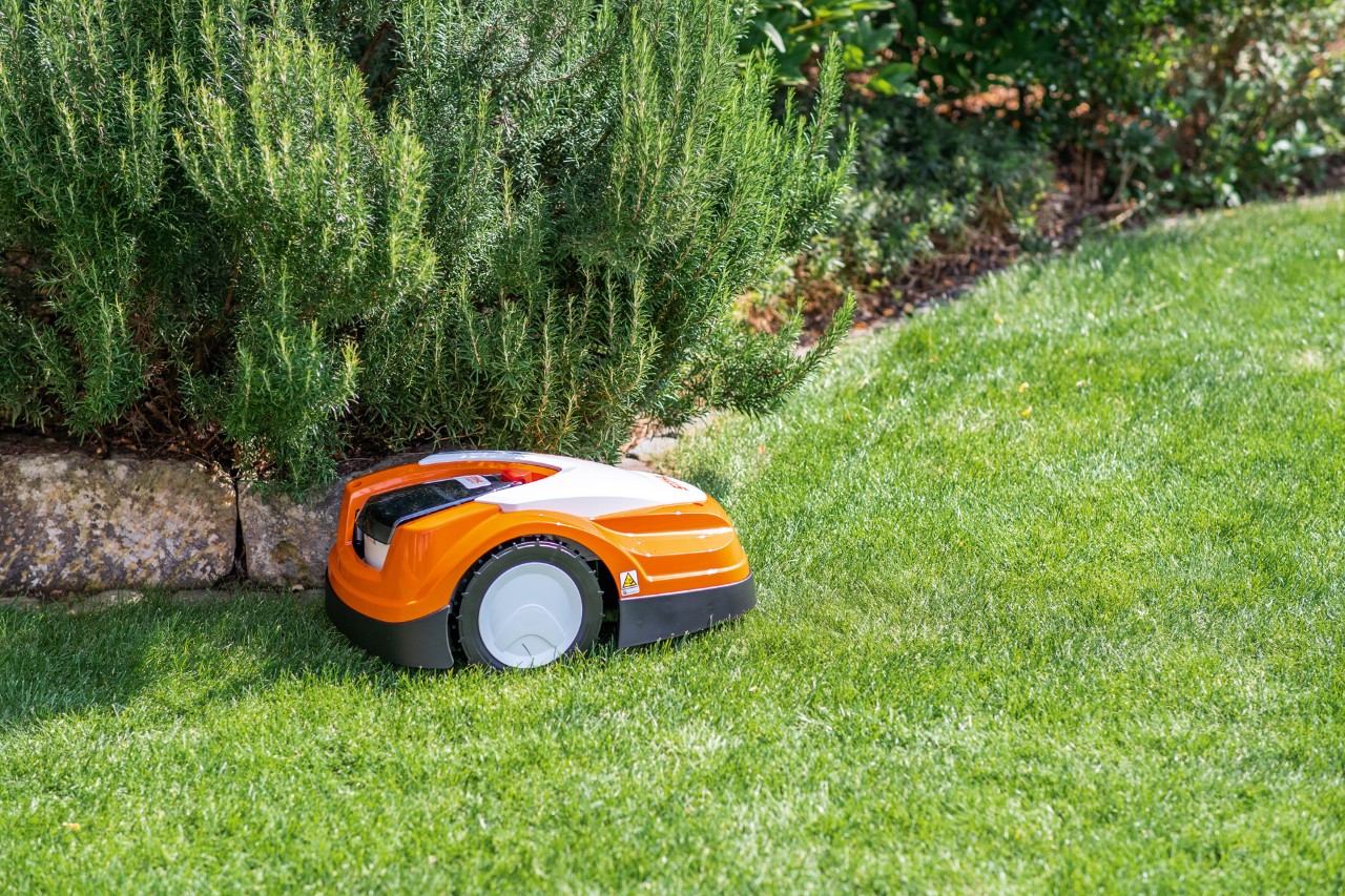 STIHL iMOW® RMI 422 PC robotmaaier op groen gazon naast een perkrand van vlakke stenen