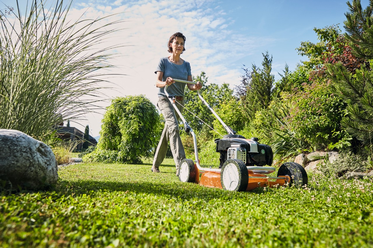 Vrouw mulcht haar gazon met een benzine mulchmaaier