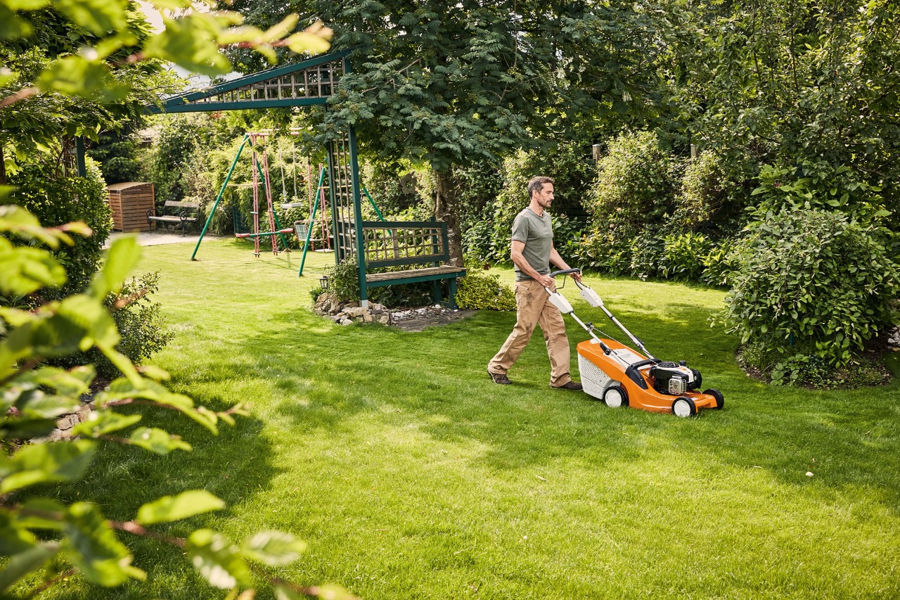 Man maait het gras met een benzine grasmachine