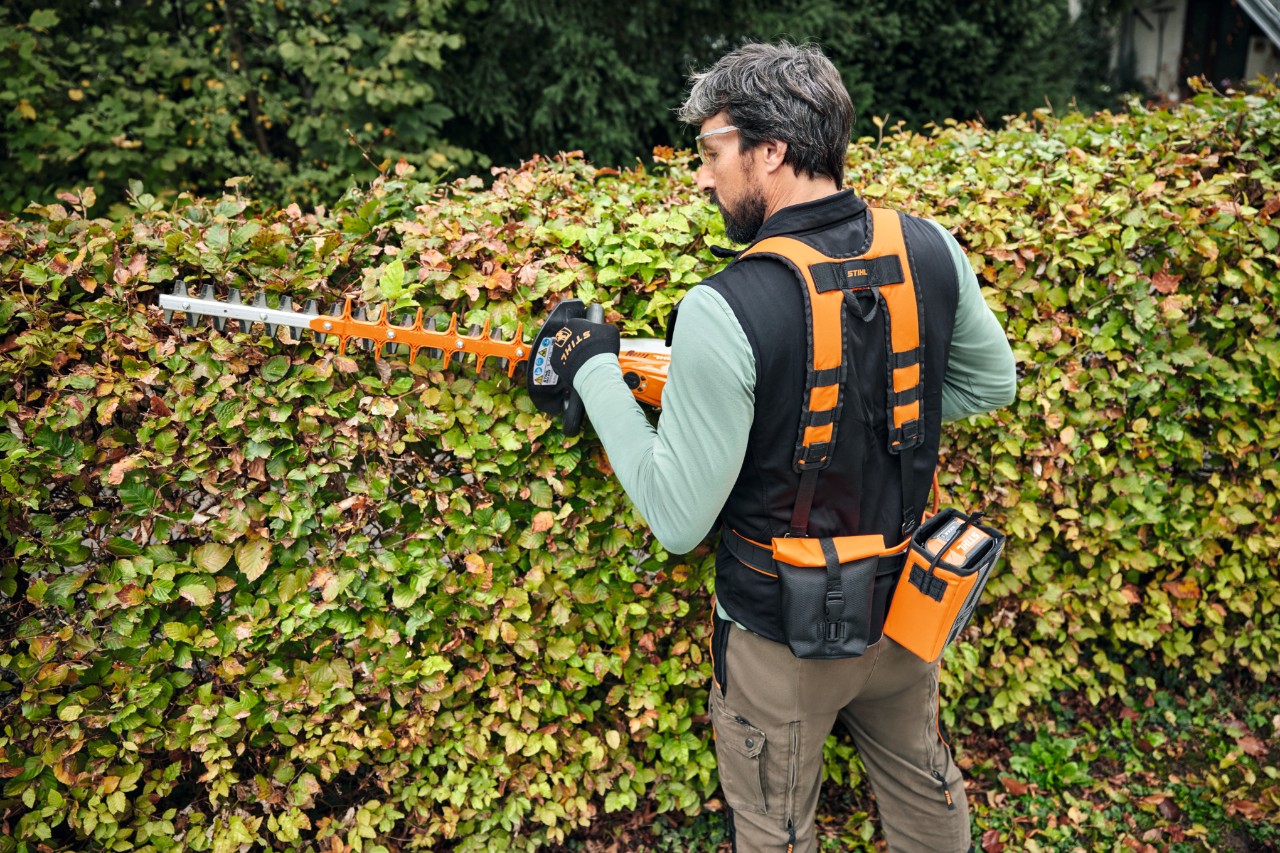 Persoon snoeit een heg met STIHL accessoires van het Advance X-Flex systeem