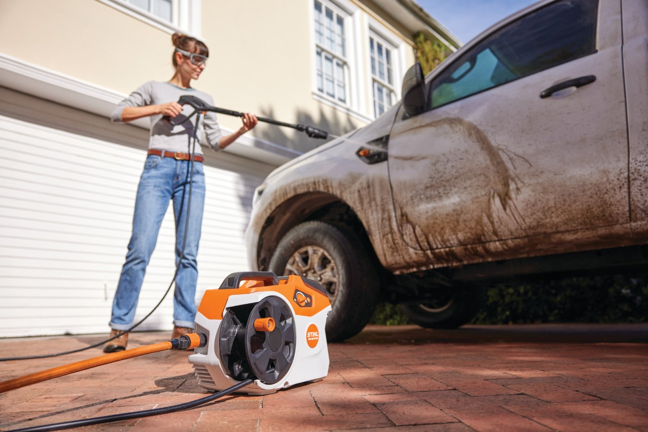 Vrouw wast een auto met de STIHL REA 60 PLUS hogedrukreiniger op accu