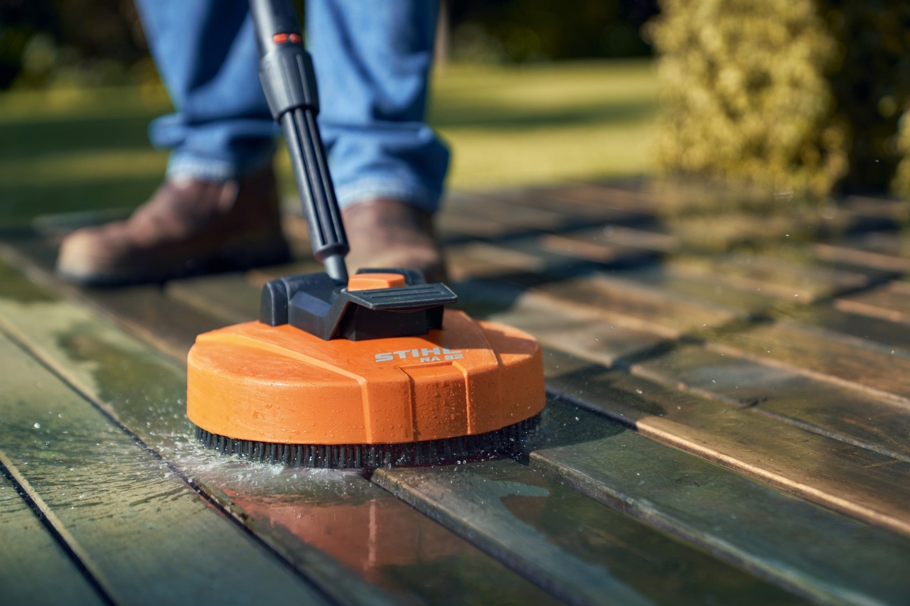 Man reinigt een houten terras met een vlakreiniger