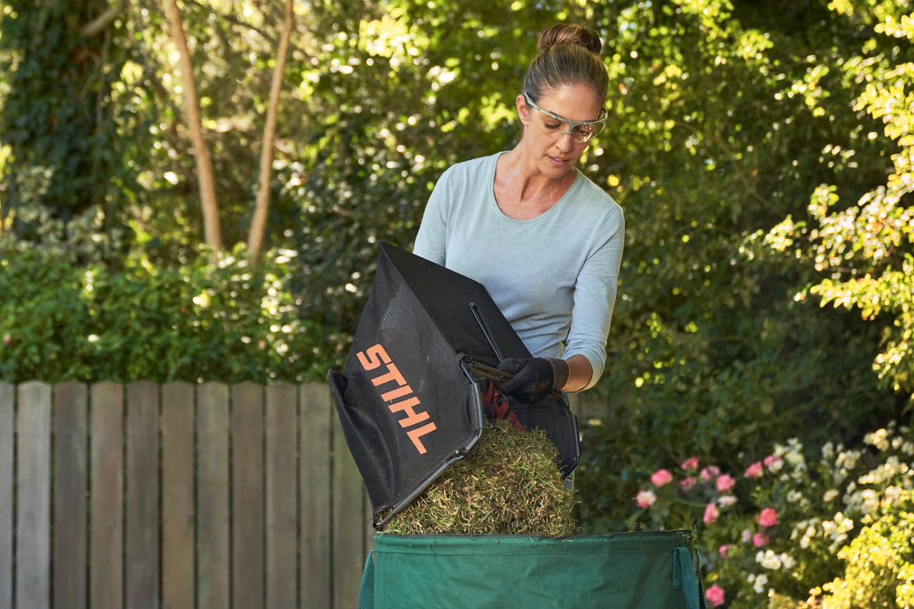 Vrouw gooit bak met maaiafval uit