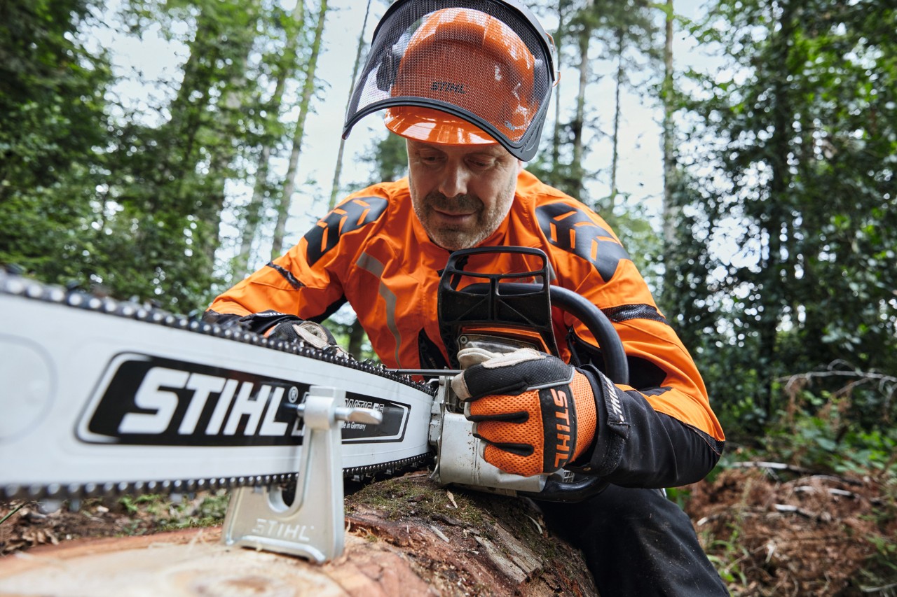Een man in beschermende uitrusting werkt met een STIHL kettingzaag in het bos