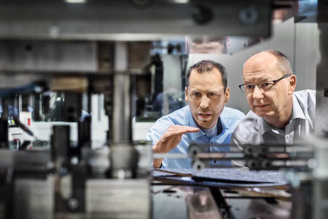 Twee mannen bekijken een installatie in de kettingfabriek