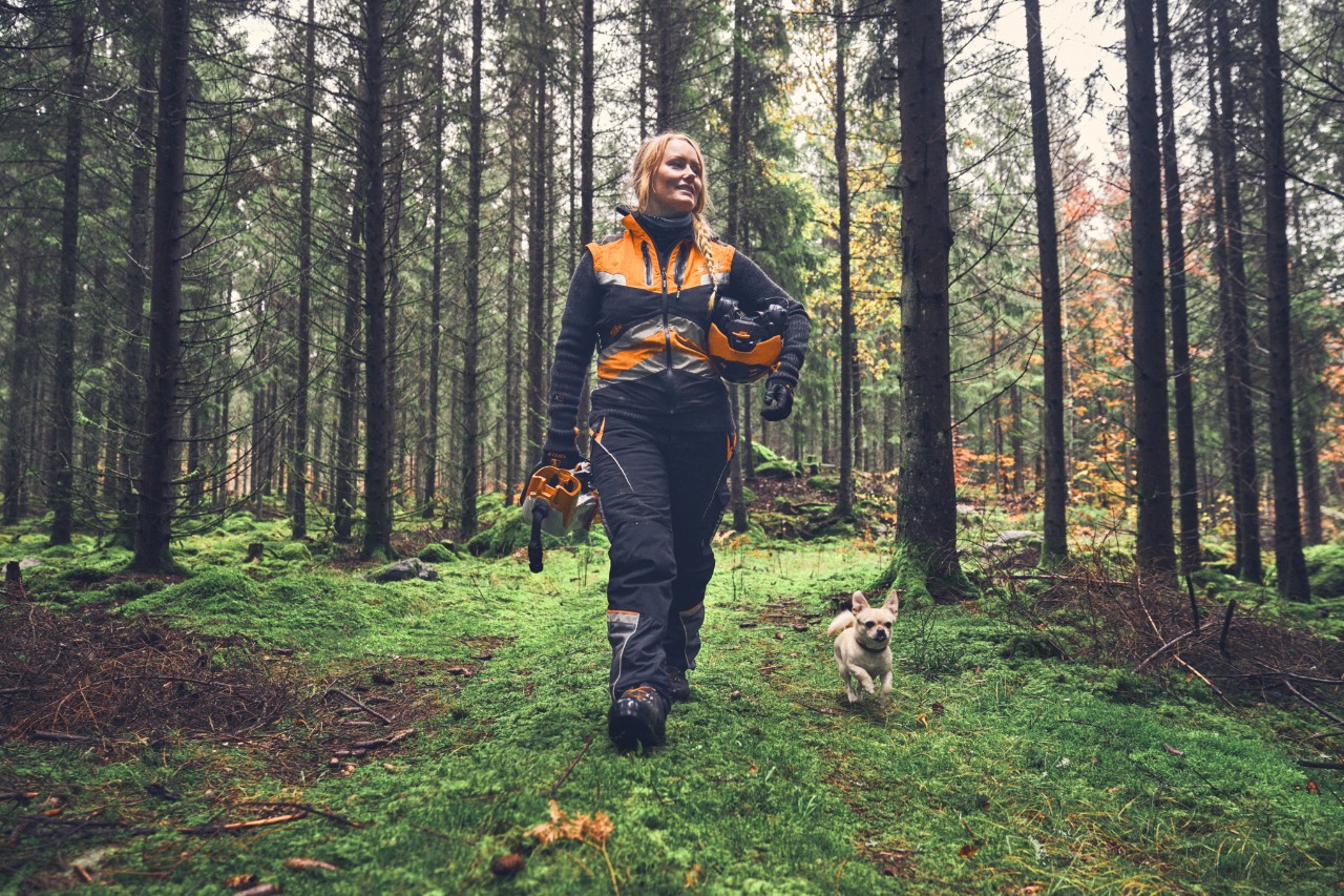 Boomverzorgster Viktoria Carstens wandelt in een bos met een hond.