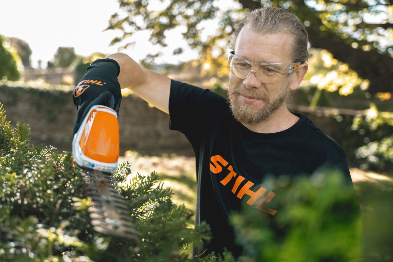 Hoofdtuinier Andrew Wain snoeit een heg met een STIHL accuheggenschaar