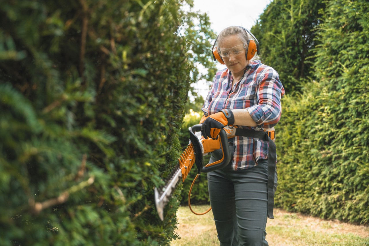 Hoofdtuinierster Aldetha Raymond snoeit een heg met een STIHL HSA 140 accuheggenschaar