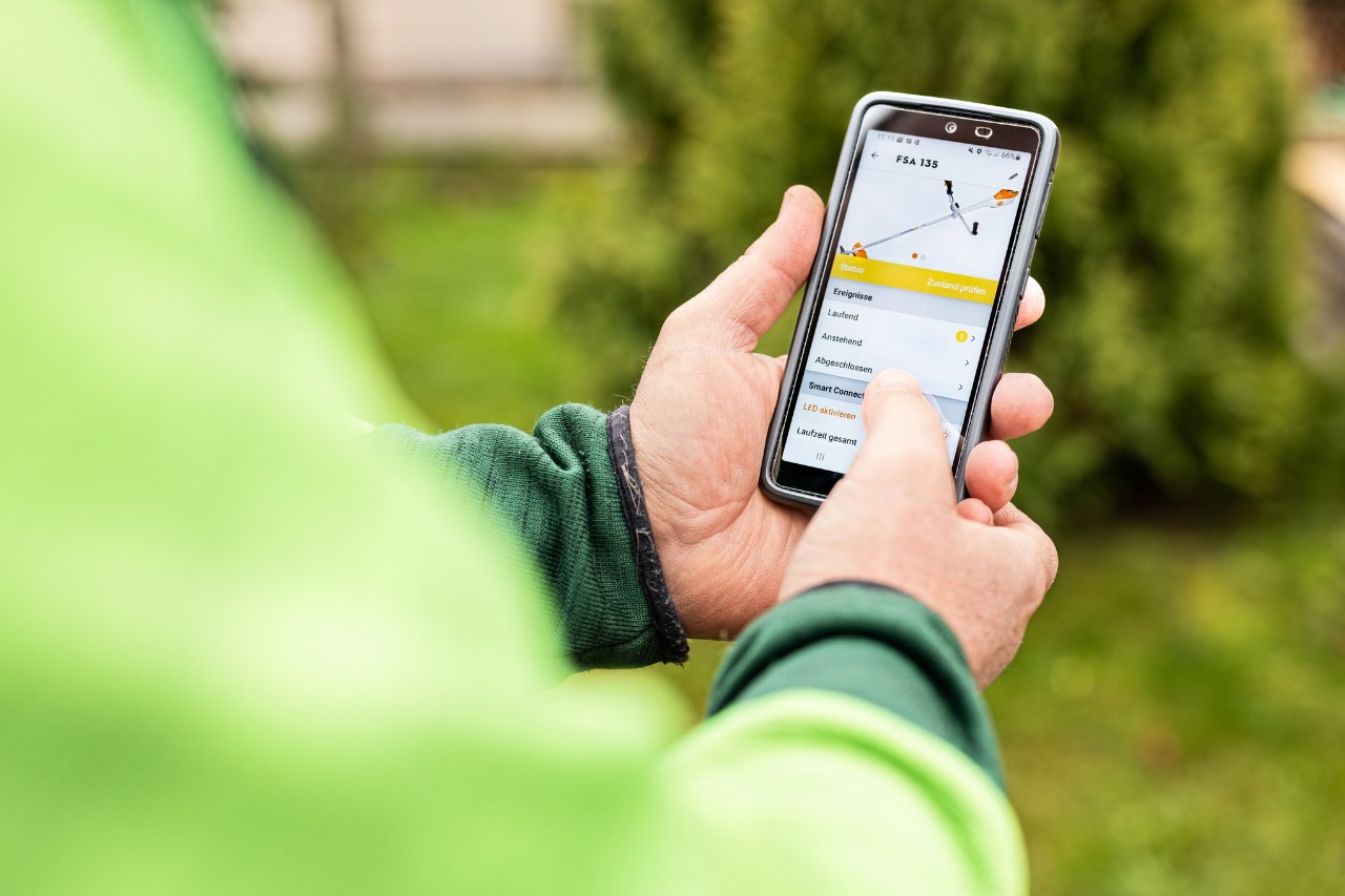 Close-up van iemand die de STIHL connected app op zijn smartphone gebruikt