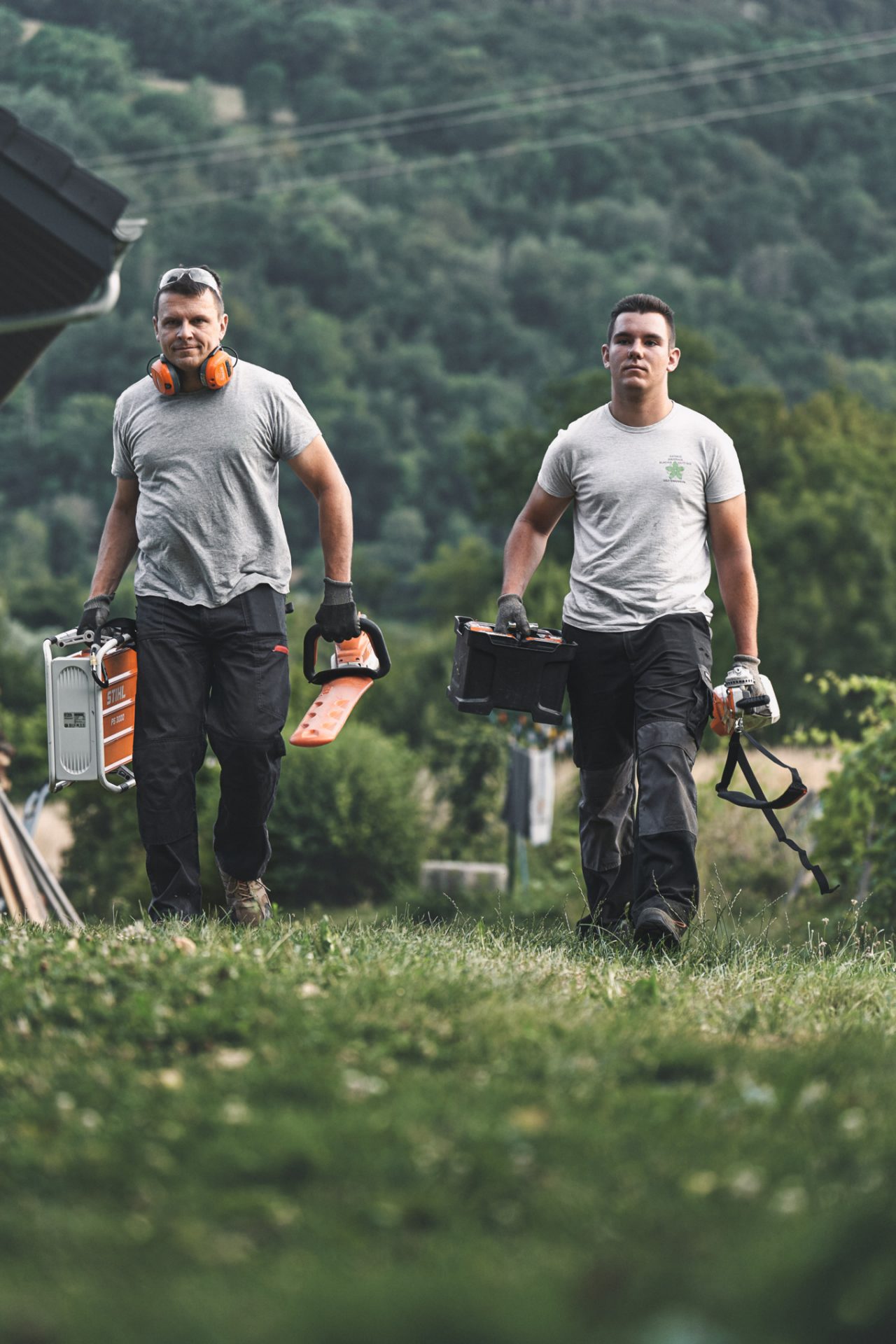 Twee professionals lopen met STIHL accumachines door een weiland