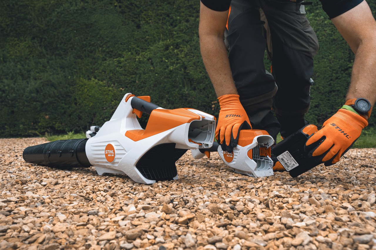 Een professional vervangt voor de heg van het Bathurst Estate de accu van zijn STIHL accubladblazer