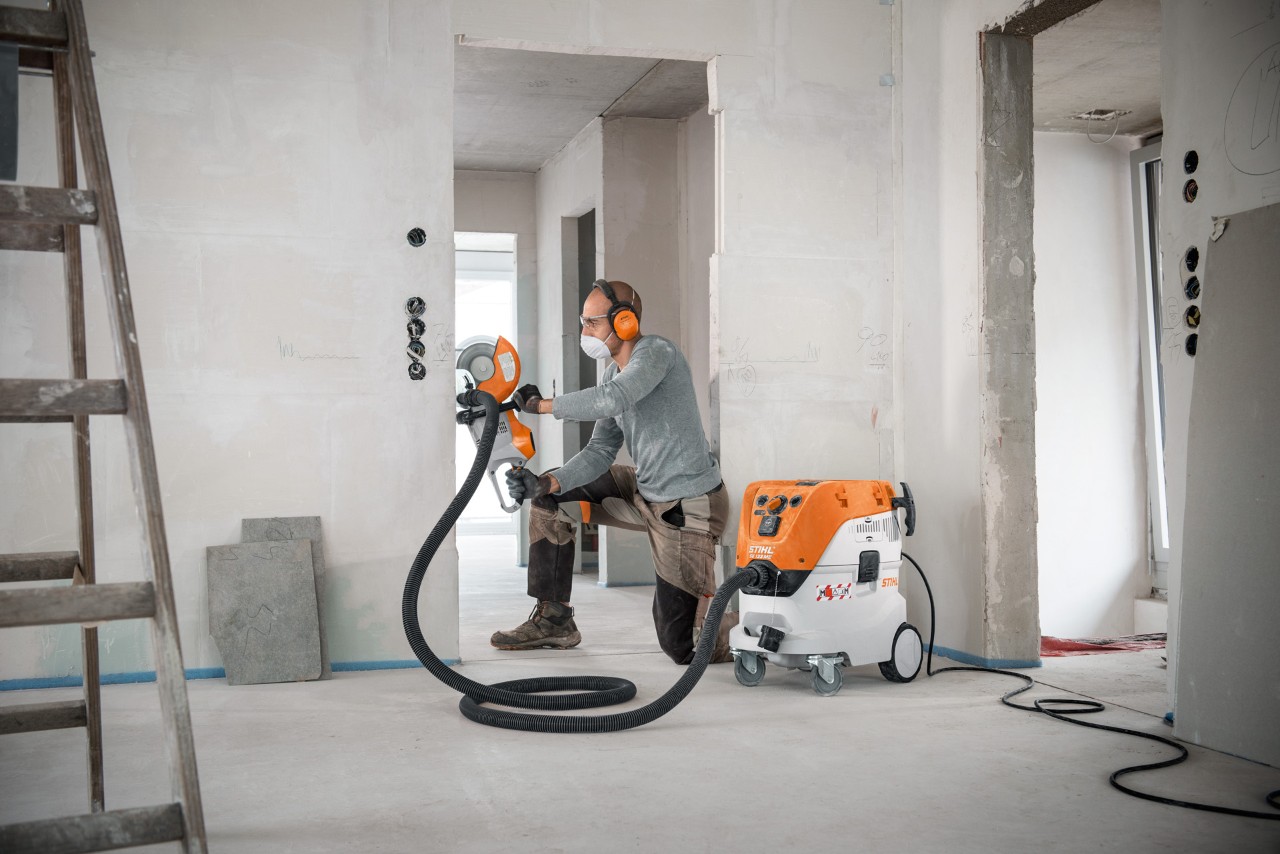 Een man gebruikt een STIHL SE 133 ME alleszuiger wanneer hij werkt met een STIHL TSA 230 doorslijpmachine