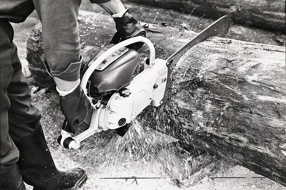 Oude zwart-witopname van iemand die met de STIHL Contra kettingzaag een boom doorzaagt 