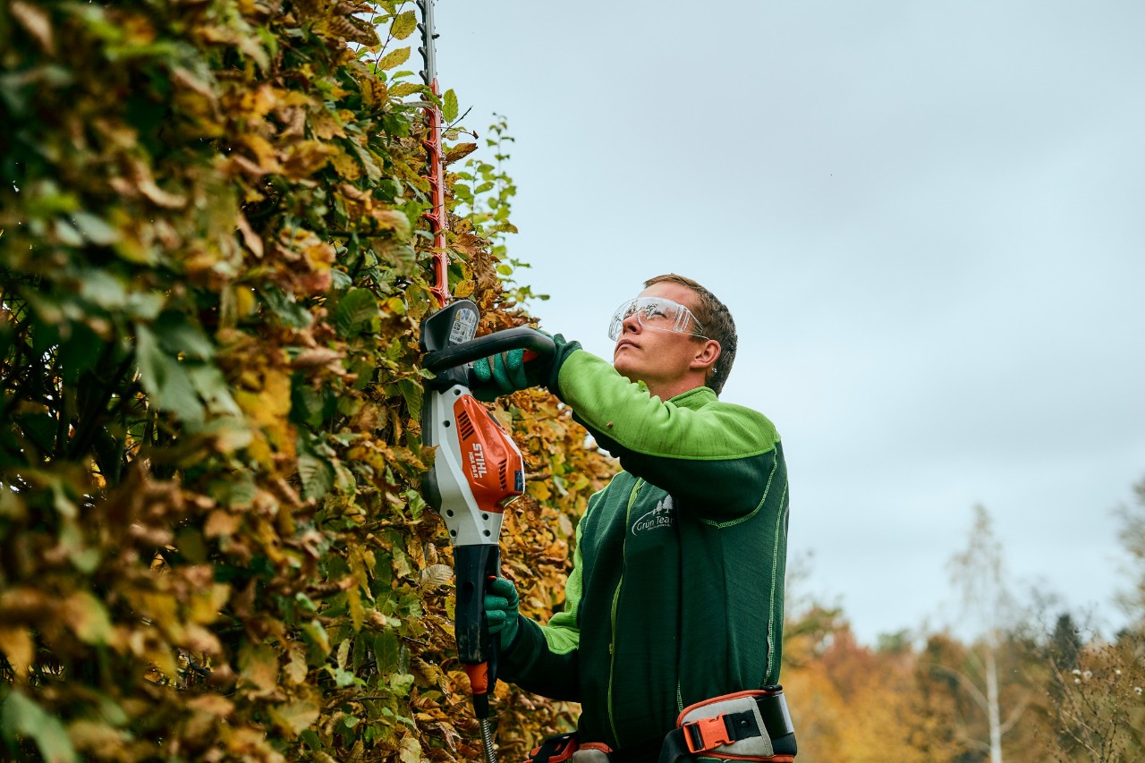 Man snoeit een heg met STIHL machine met connected