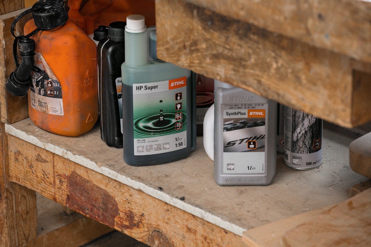 STIHL SynthPlus kettingsmeerolie en STIHL HP Super tweetaktmotorolie naast andere bedrijfsstoffen in een rek