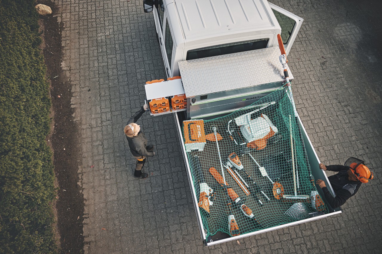 Twee professionals van STIHL in vogelperspectief bij een voertuig, beladen met bottTainer en STIHL accumachines.