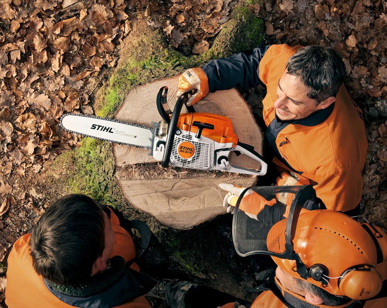 Drie mannen zitten rond een STIHL benzinekettingzaag MS 261 met gereedschapsloze tankdop