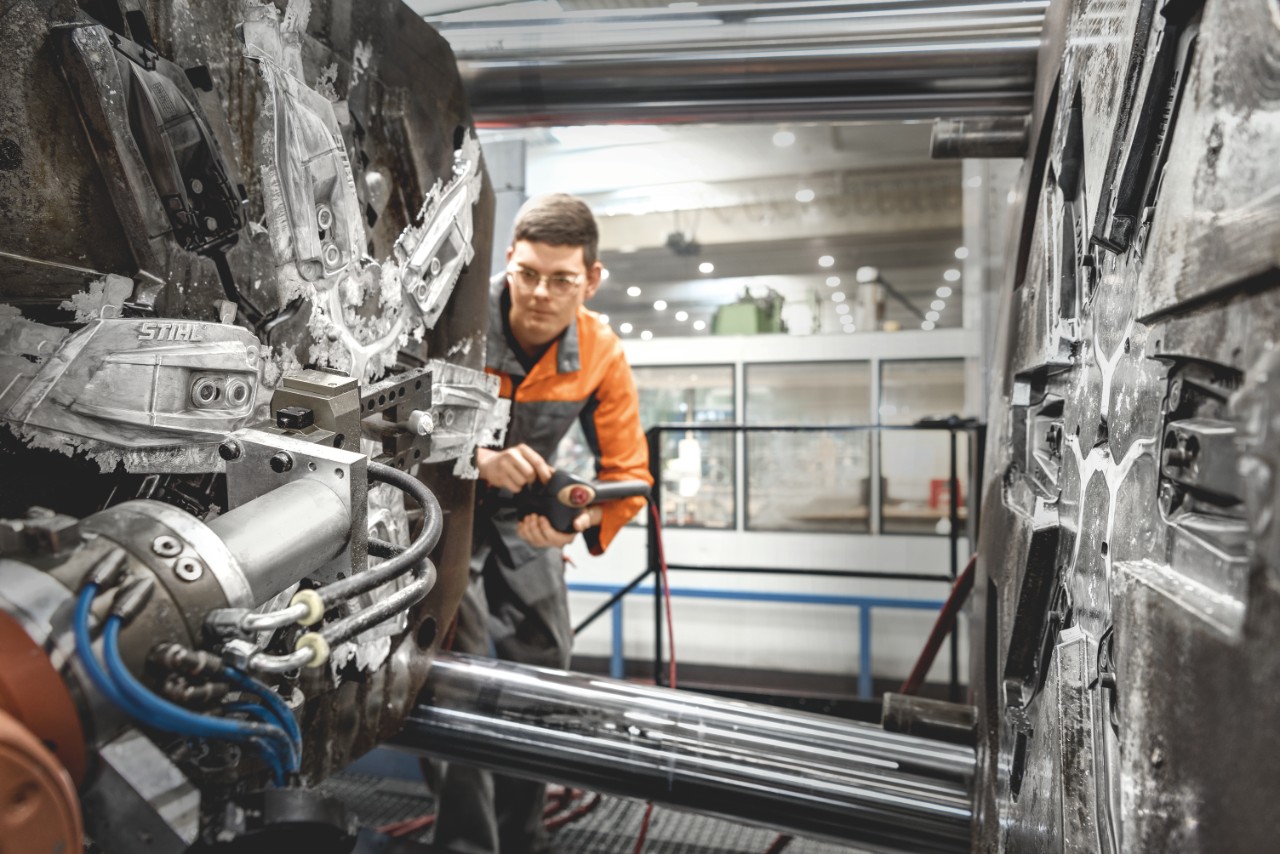 Persoon bedient machine voor het drukgietproces in de STIHL fabriek in Prüm