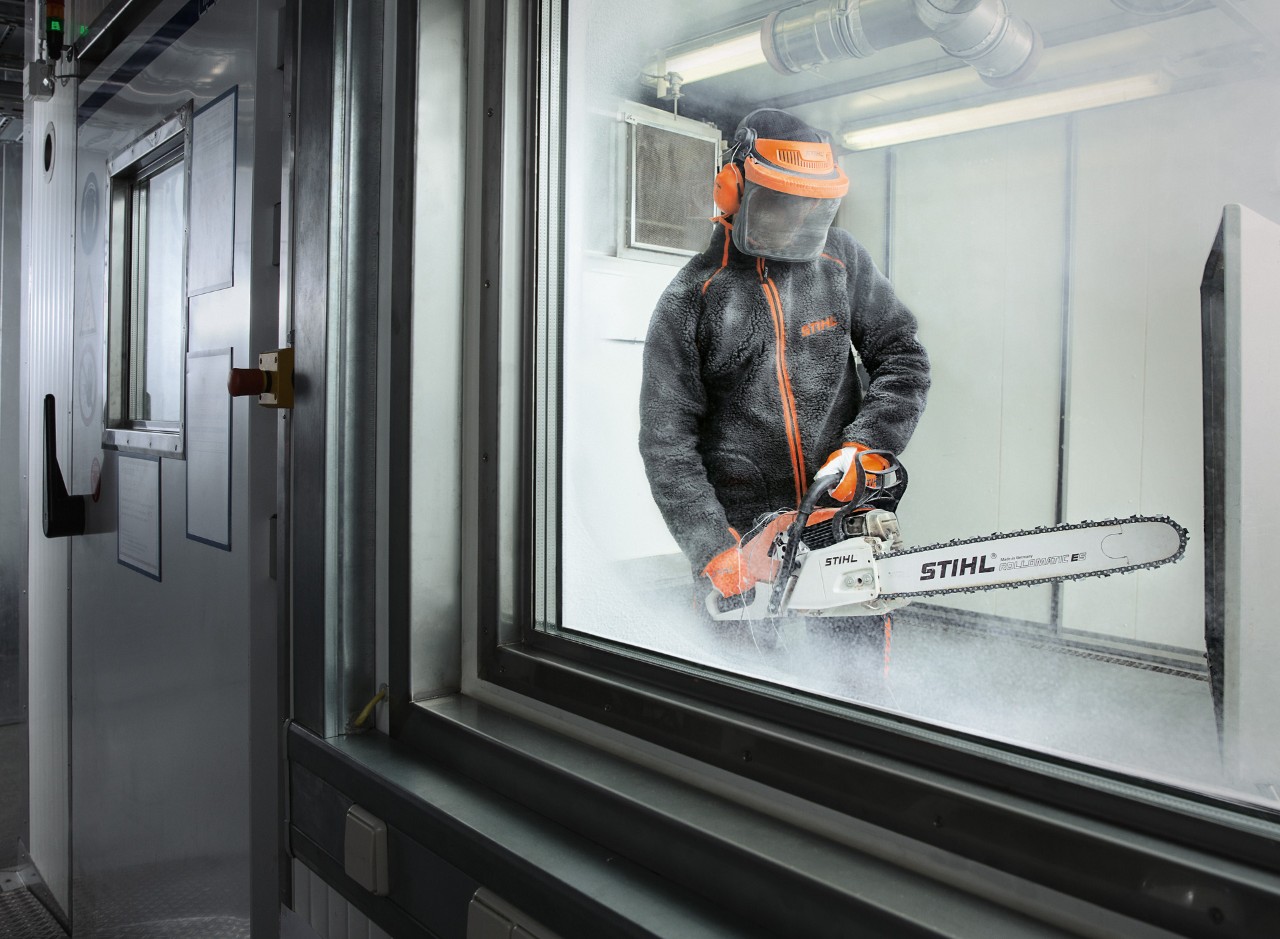 Persoon in beschermende kleding test STIHL kettingzaag in een klimaatkamer