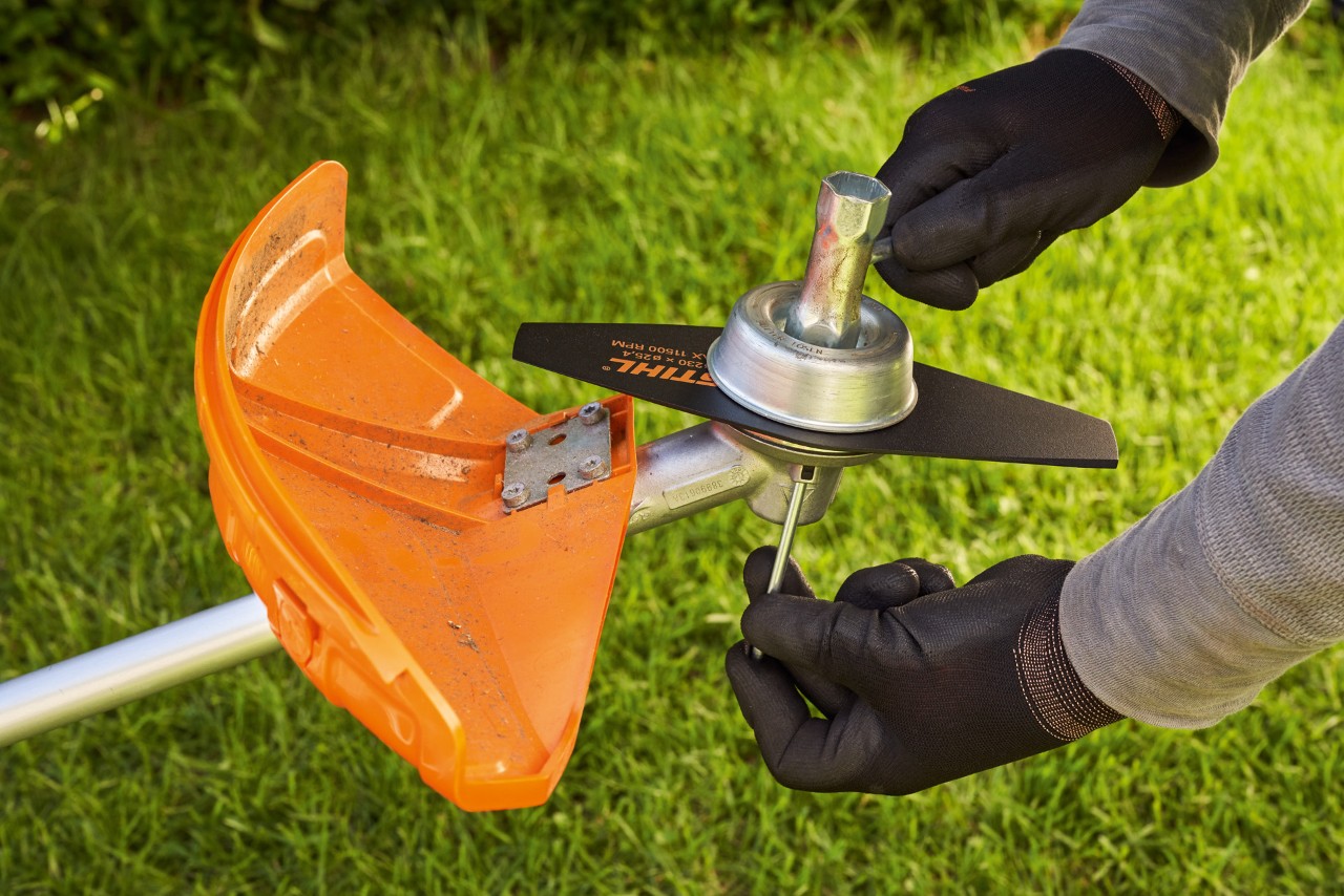 Iemand met veiligheidshandschoenen controleert het metalen gereedschap van een bosmaaier