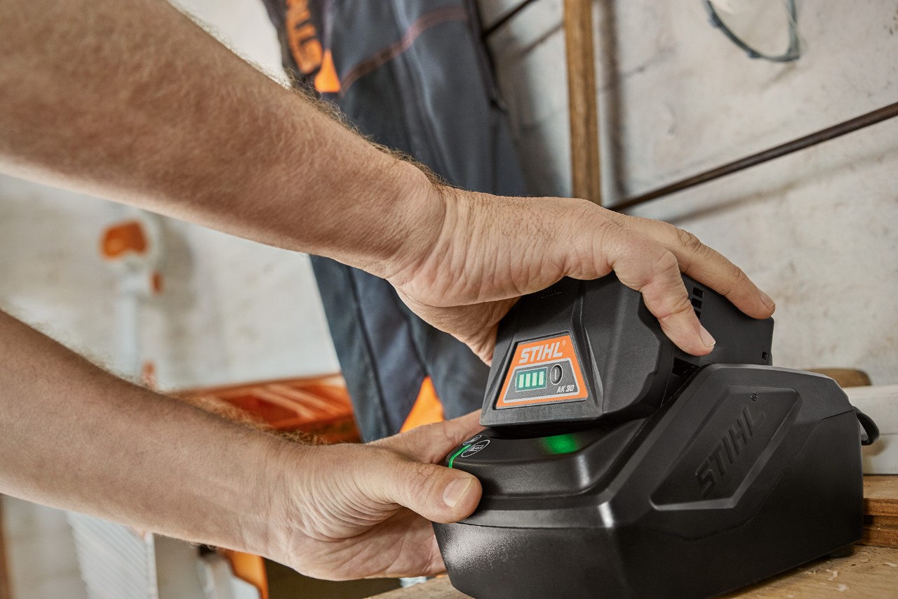 Iemand neemt de STIHL AK 30 accu uit de lader