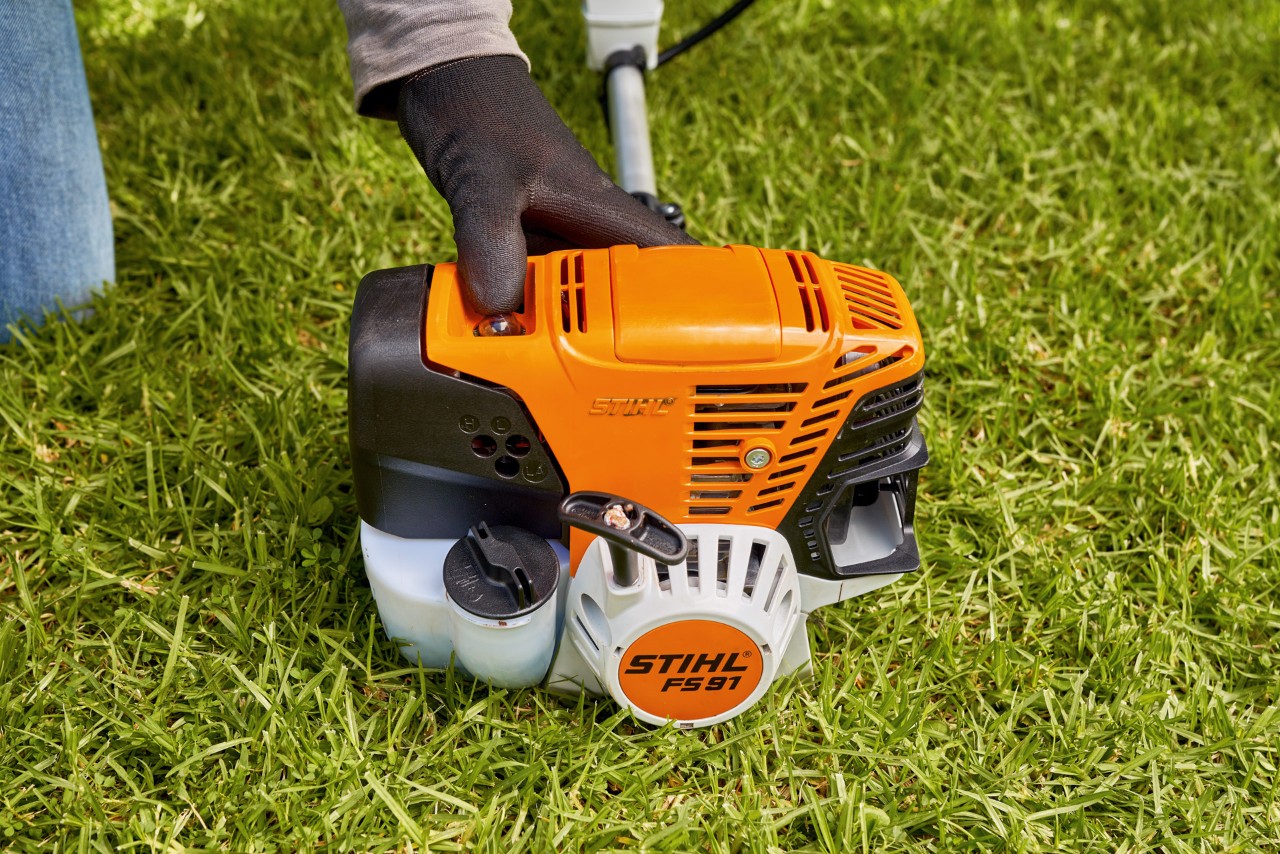 Man drukt de brandstofpomp van de STIHL FS 91 benzinebosmaaier in om deze te starten