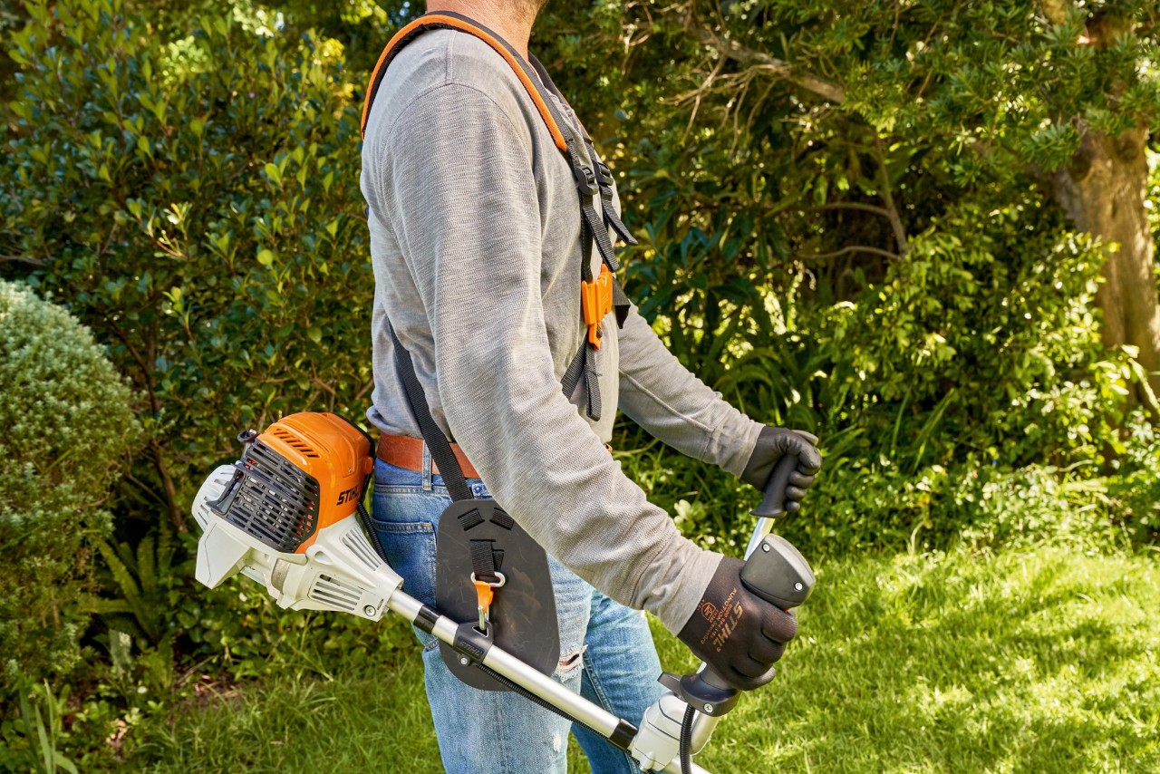 Man tilt de STIHL FS 91 benzinebosmaaier van de grond op om te beginnen maaien 