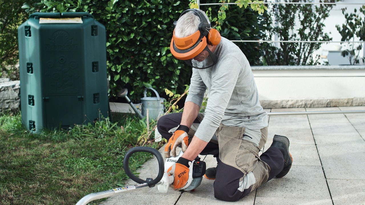 Iemand in veiligheidskleding drukt de STIHL FS 38 benzinegrastrimmer op de grond