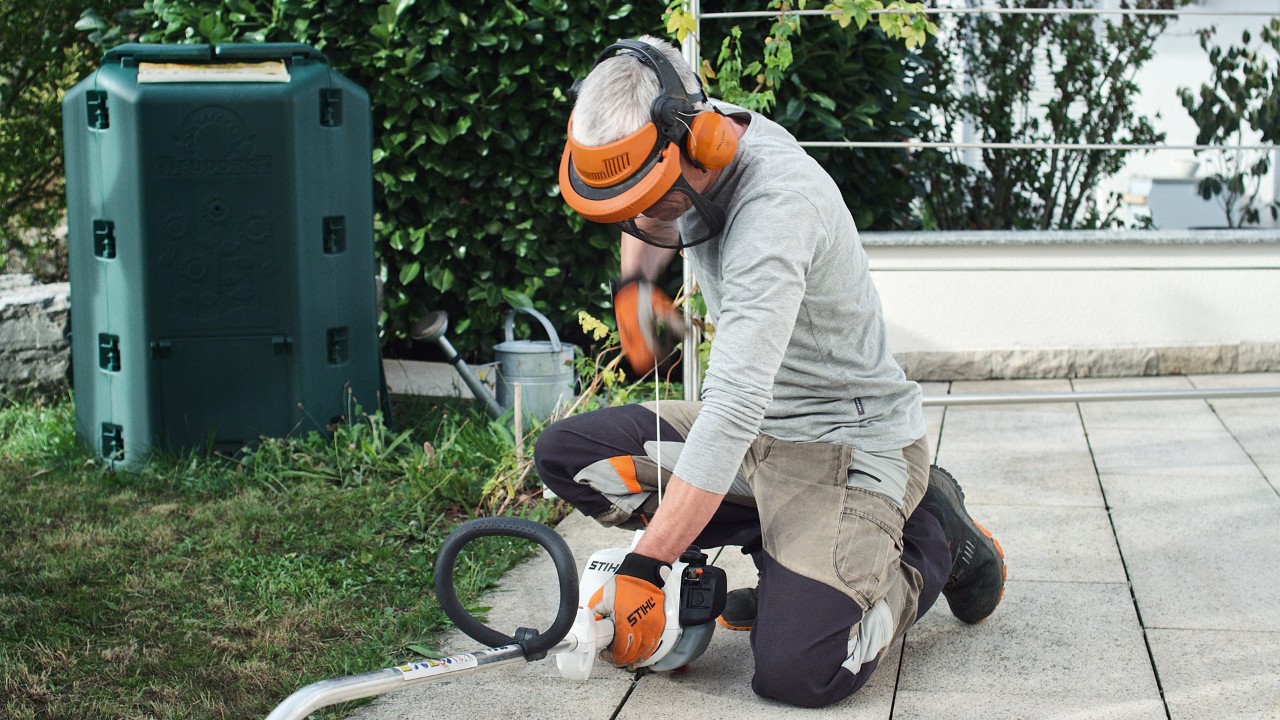 Iemand in veiligheidskleding trekt aan het startkoord van de STIHL FS 38 benzinegrastrimmer