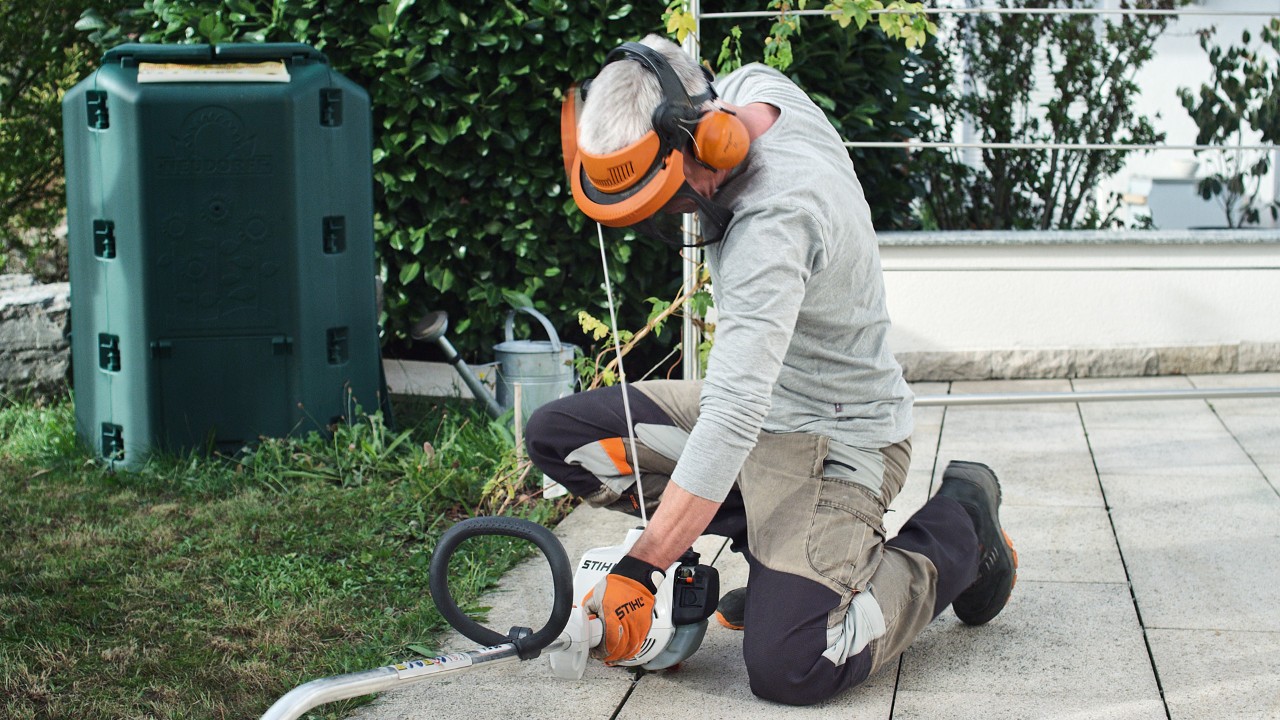 Iemand in veiligheidskleding trekt opnieuw aan het startkoord van de STIHL FS 38 benzinegrastrimmer