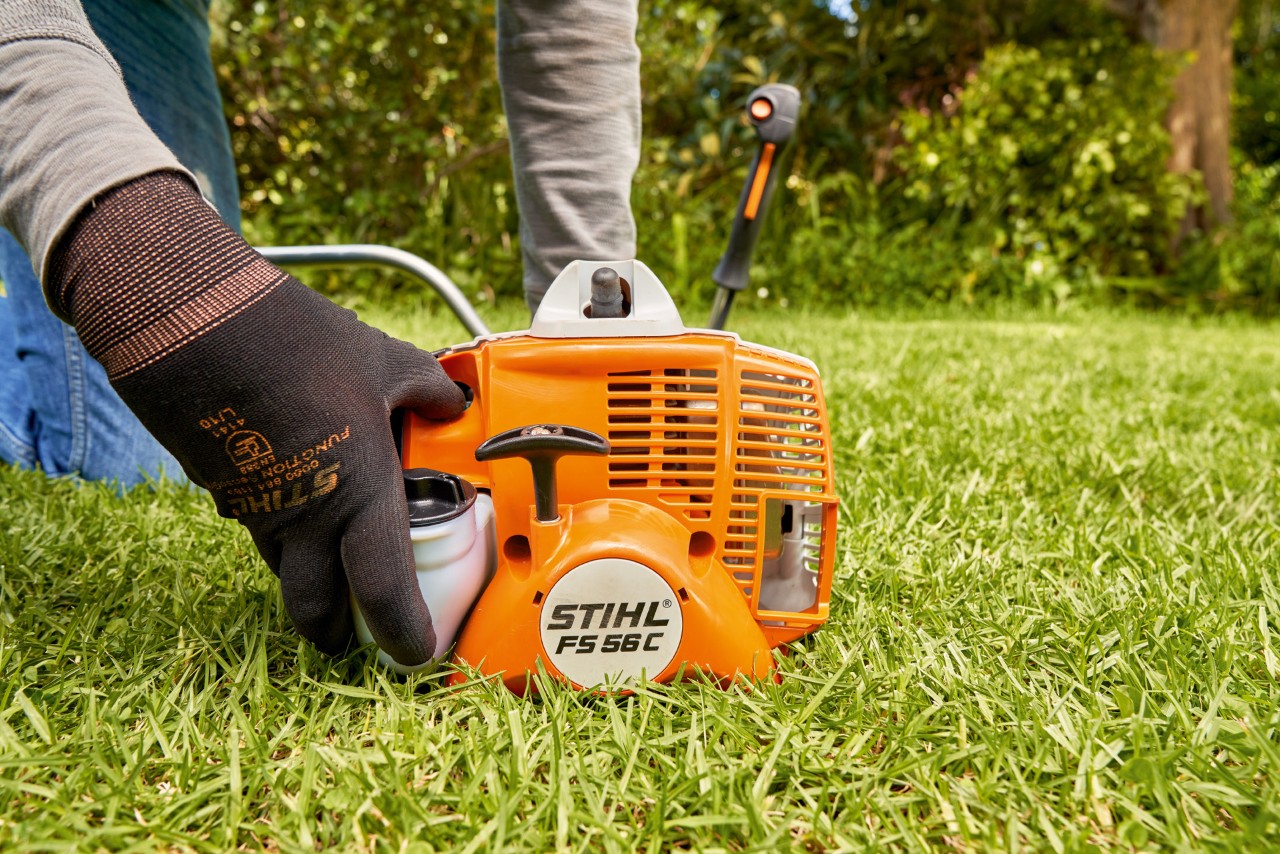 Man drukt de brandstofpomp van de STIHL FS 56 benzinekantenmaaier in om deze te starten