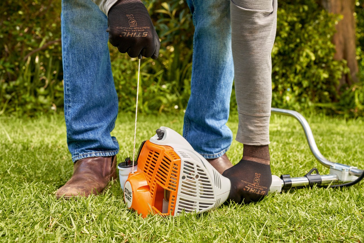 Man trekt aan het startkoord van de STIHL FS 56 benzinekantenmaaier 