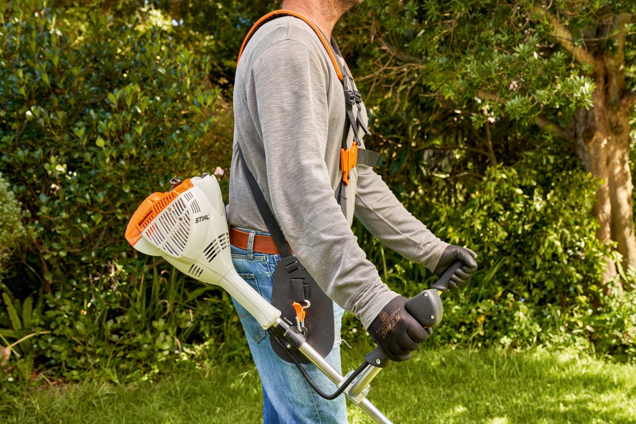 Man tilt de STIHL FS 56 benzinekantenmaaier van de grond