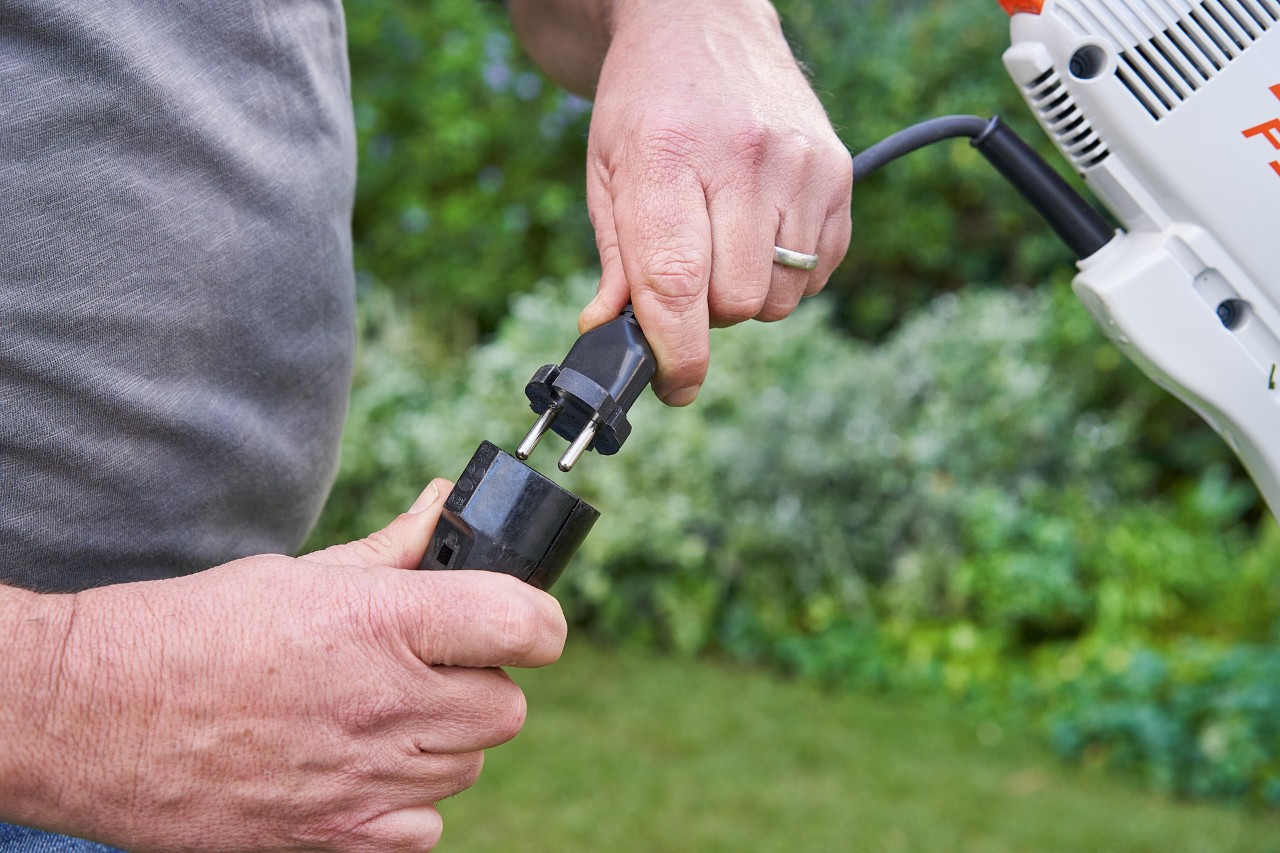Man met veiligheidshandschoenen bedient de gashendel van de STIHL FSE 60 elektrische kantenmaaier om deze te starten
