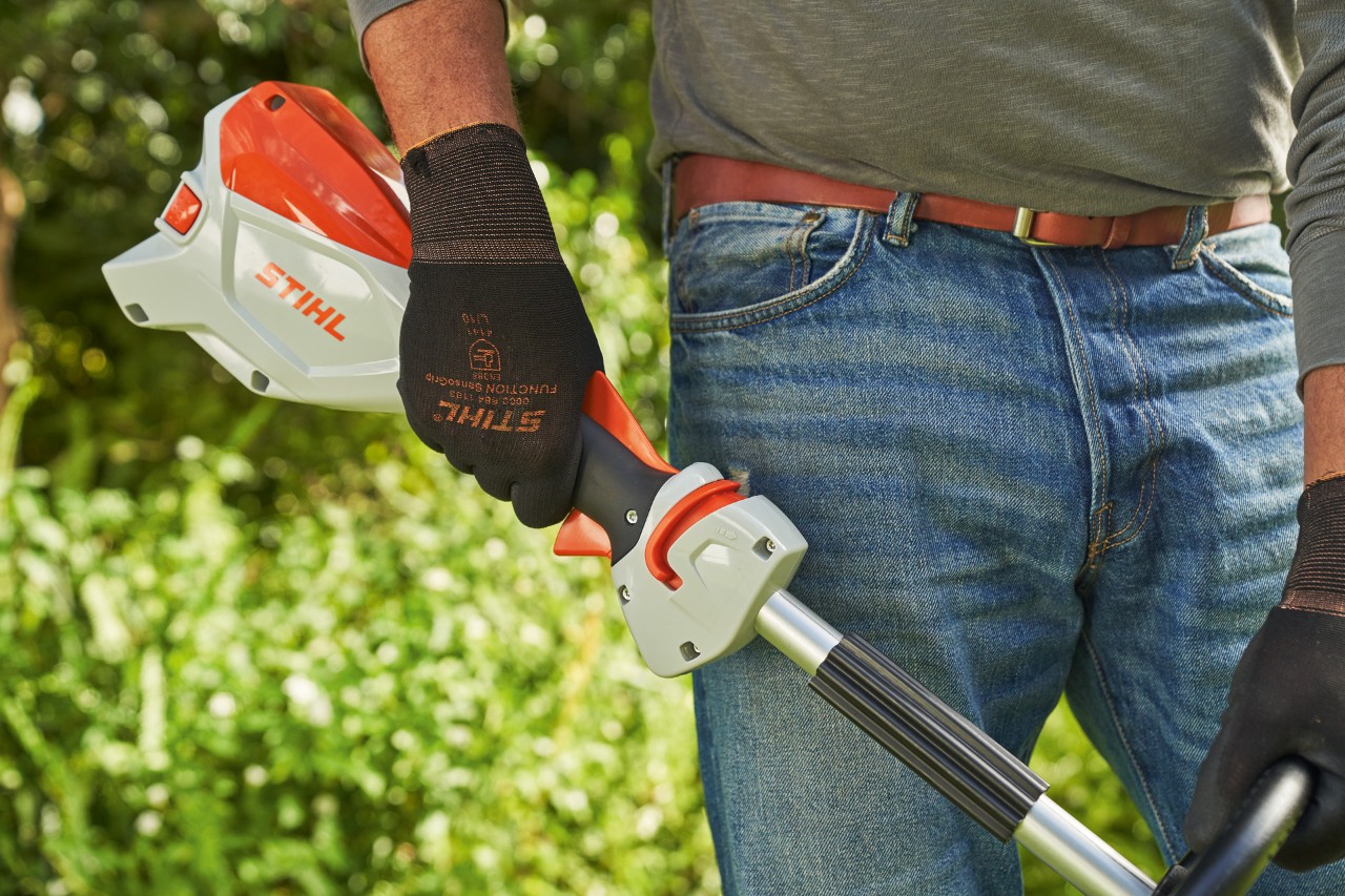 Man met veiligheidshandschoenen laat de gashendel van de STIHL FSA 60 accugrastrimmer los  om deze uit te schakelen