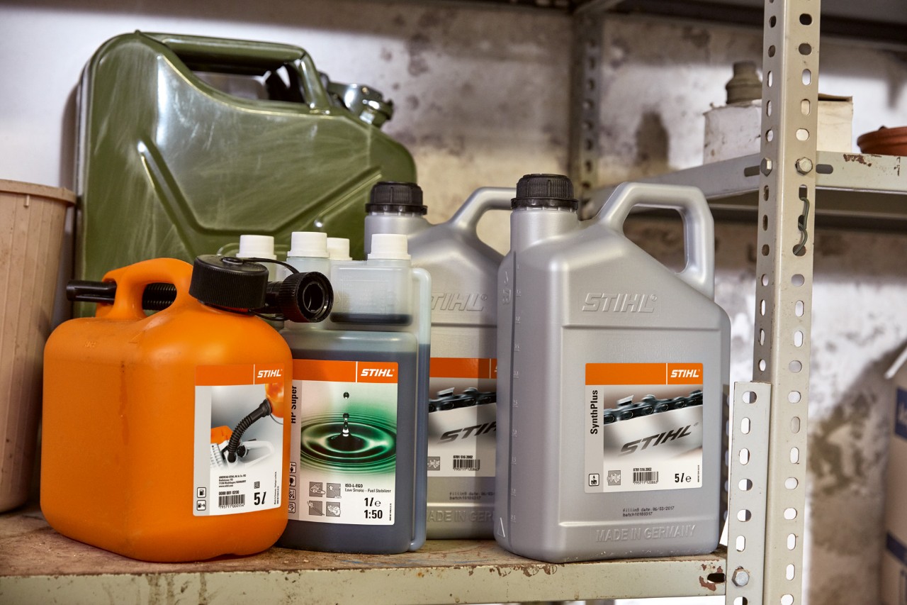 Lichtgekleurde jerrycan met STIHL tweetaktolie HP Super en oranje jerrycan met een bosmaaiermengsel.