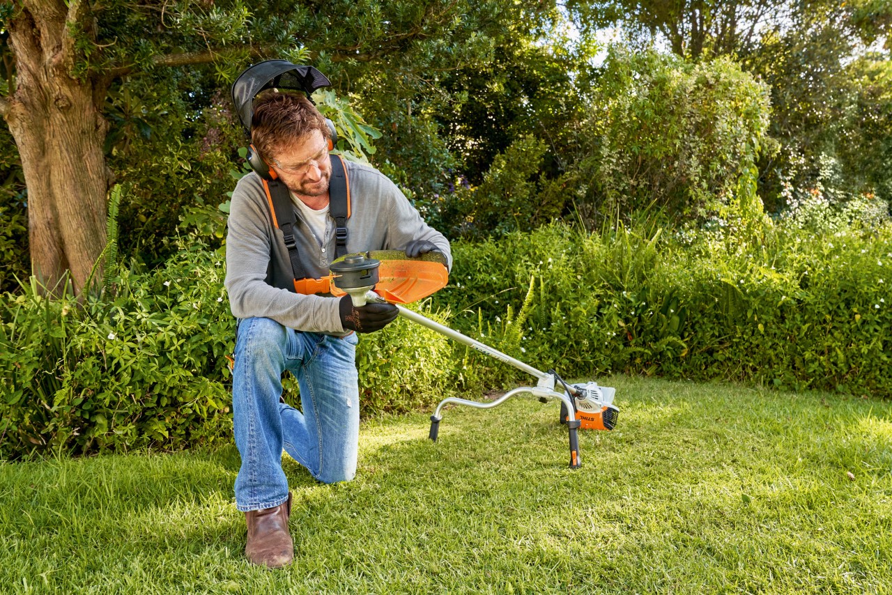 Man bereidt in de tuin een bosmaaier voor om het snijgarnituur te vervangen.