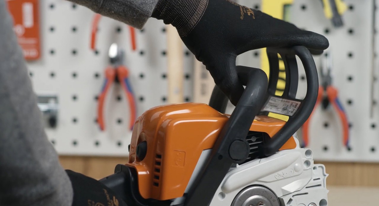 Handbeschermer van een STIHL MS 170 kettingzaag wordt naar de draagbeugel getrokken om de kettingrem te ontspannen
