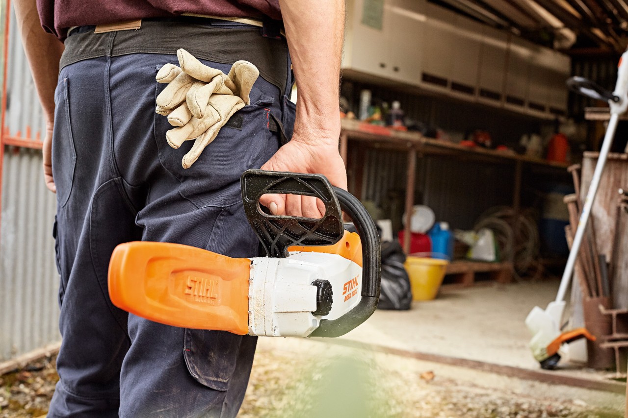 Man staat met STIHL accukettingzaag voor werkplaats