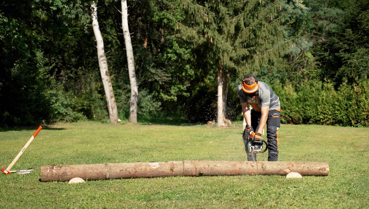 Persoon gebruikt een STIHL kettingzaag om een boomstam tot brandhout te zagen.