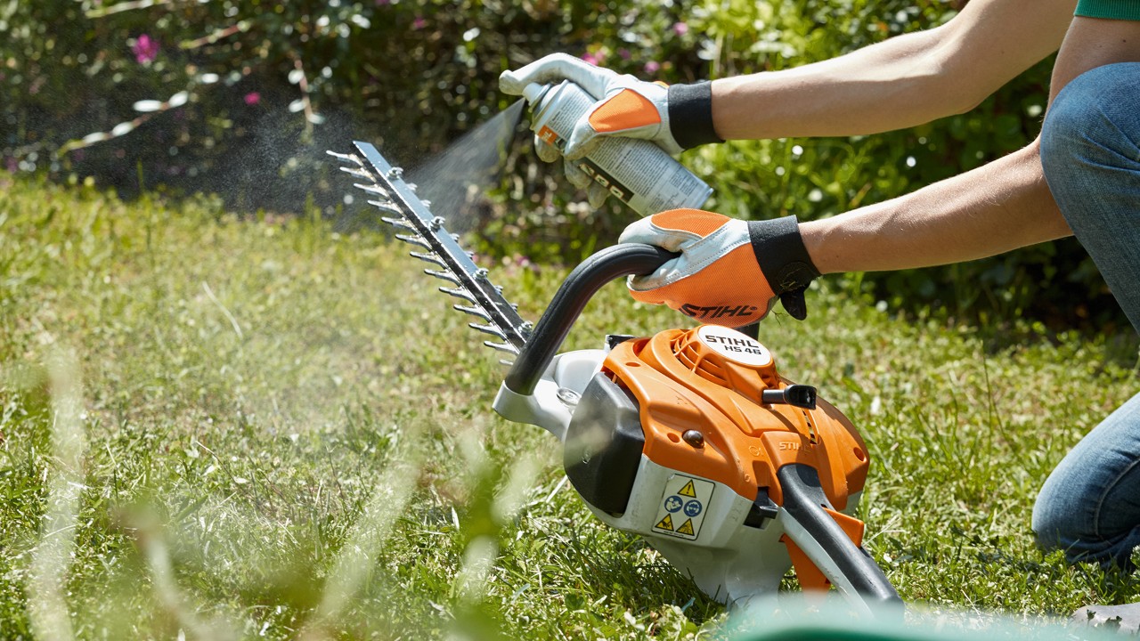STIHL benzineheggenschaar HS 82 T wordt op groen gazon ingespoten om deze te reinigen