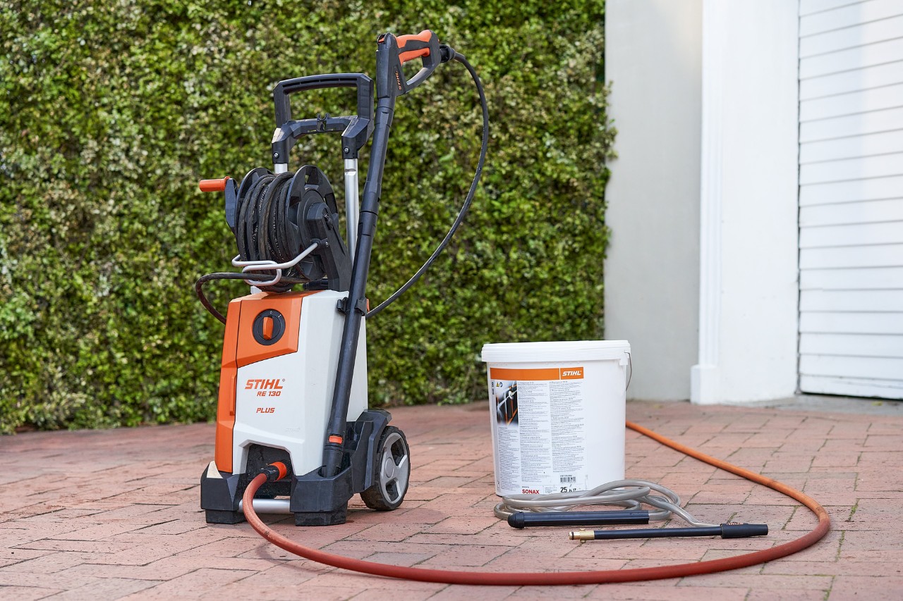 Voor een garage staan hogedrukreiniger STIHL RE 130 PLUS en straalgranulaat SB 90 voor natstralen 
