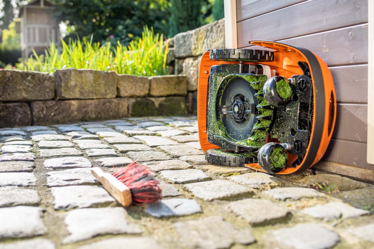 STIHL iMOW® robotmaaier op zijn zijkant gekanteld, klaar voor een reinigingsbeurt