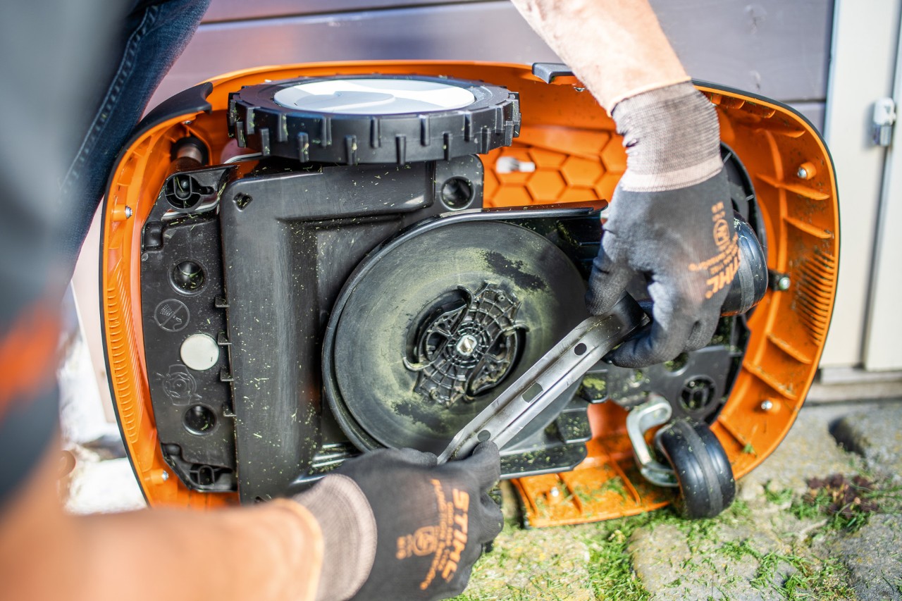 het maaimes van een STIHL iMOW® robotmaaier die op zijn kant ligt, wordt gecontroleerd.