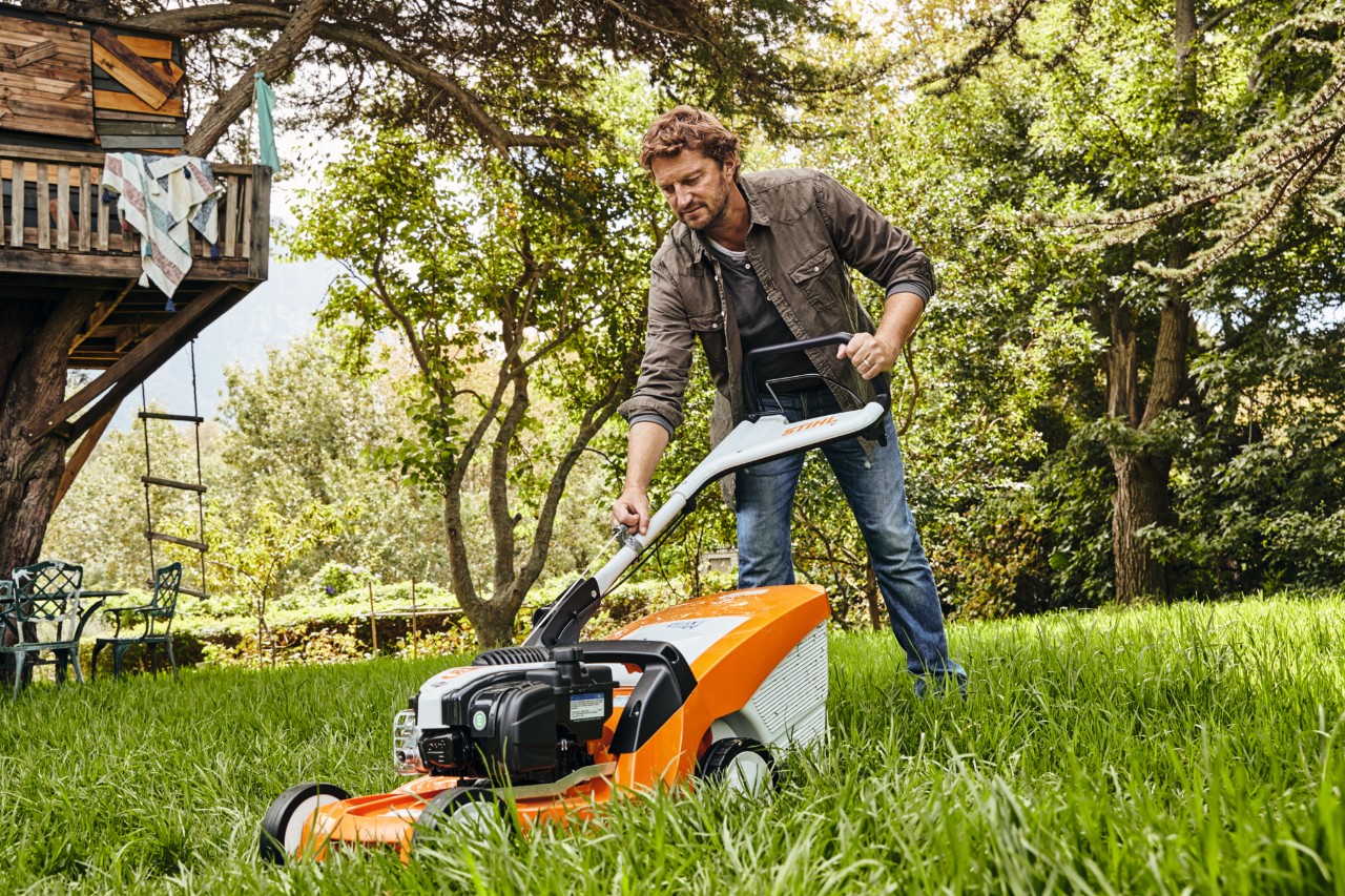 Een man maait een tuinweide met de STIHL RM 448 TC benzinegrasmaaier