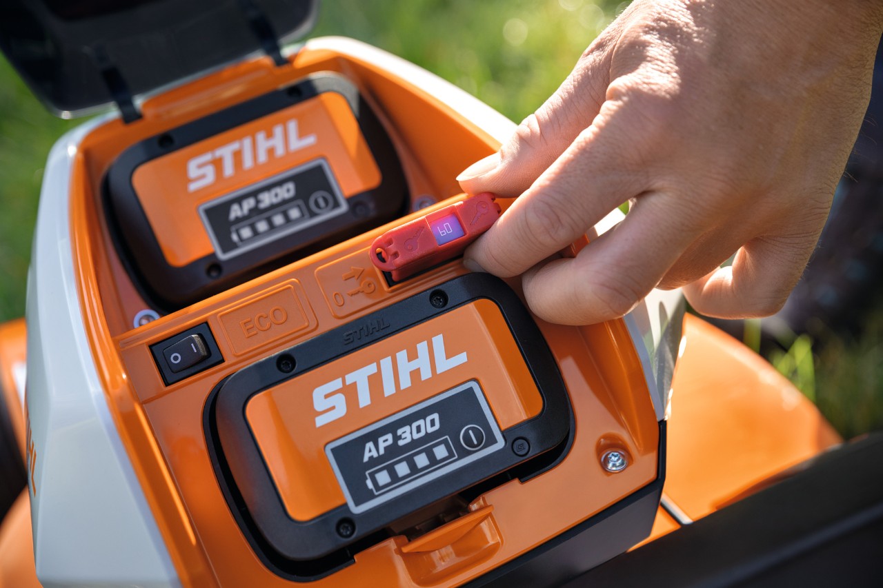 Iemand sluit een veiligheidsstekker in de STIHL RMA 448 VC accugrasmaaier aan 