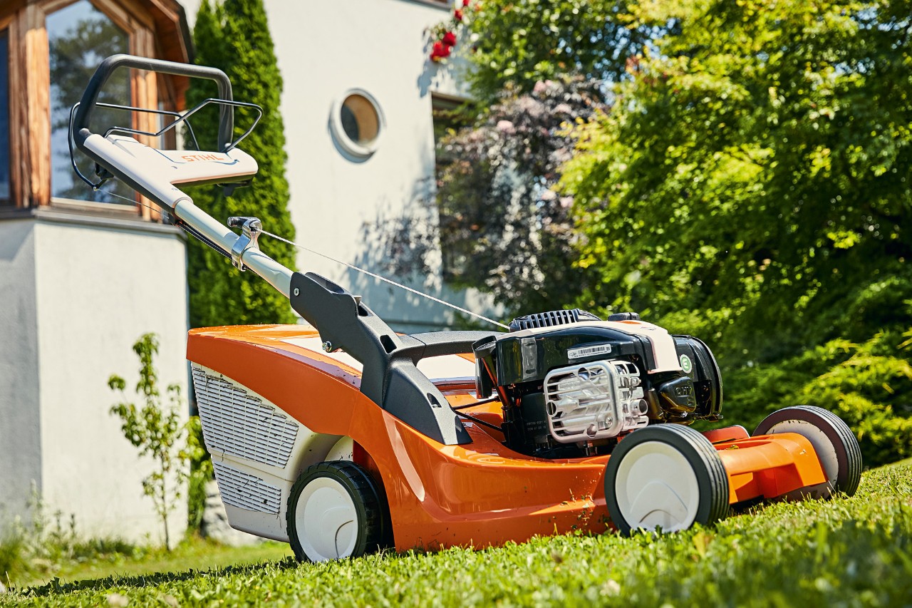 STIHL RM 443 T benzinegrasmaaier op groen gazon voor een woning.