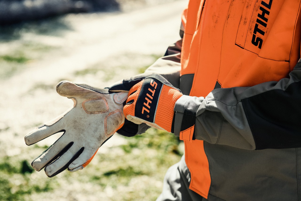  Close-up van een persoon die STIHL werkhandschoenen aantrekt.