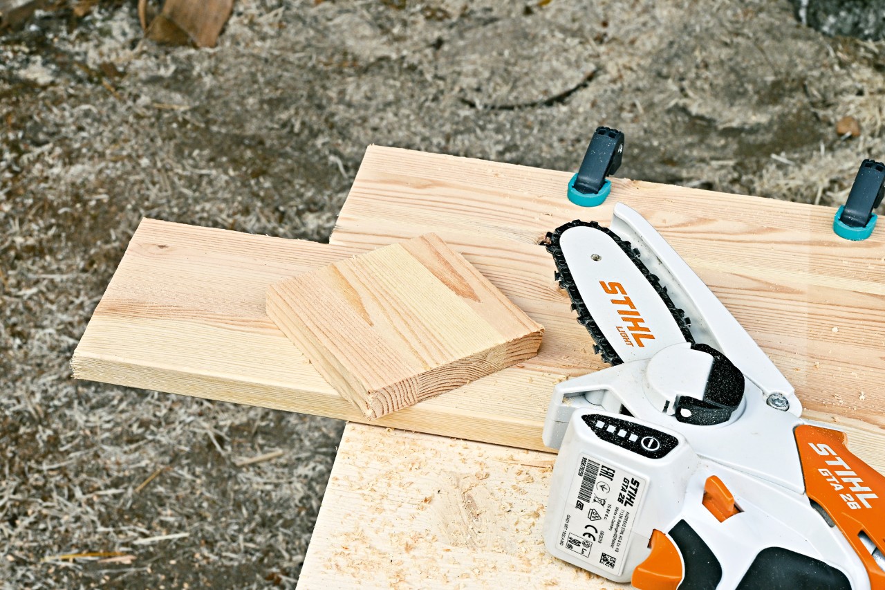 STIHL GTA 26 accusnoeizaag naast een stuk hout waaruit een vierkant is gezaagd 